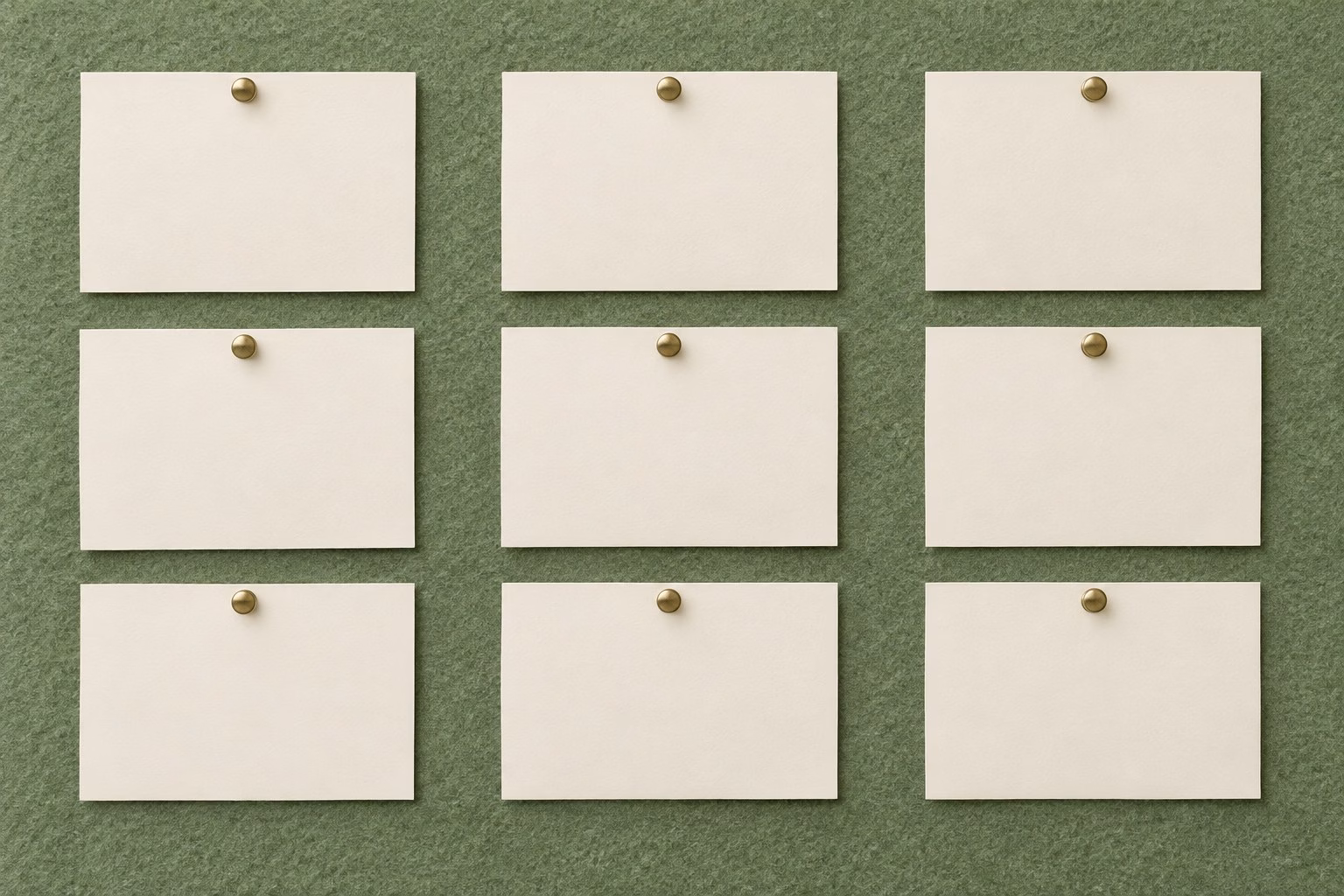 An overhead editorial flat-lay of three neat vertical columns of blank cream cards pinned to a muted sage-green felt board, seen from directly above.