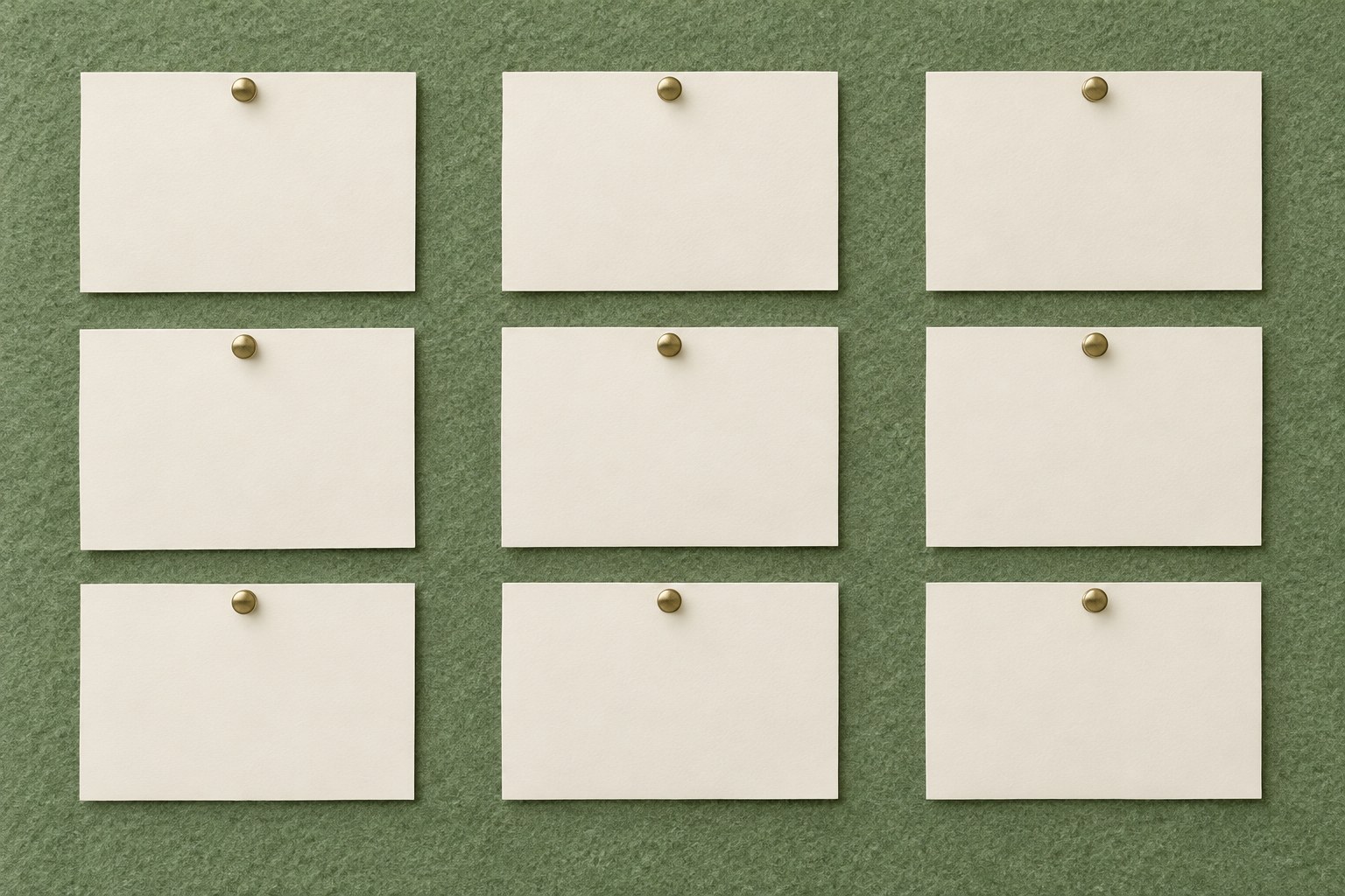 An overhead editorial flat-lay of three neat vertical columns of blank cream cards pinned to a muted sage-green felt board, seen from directly above.