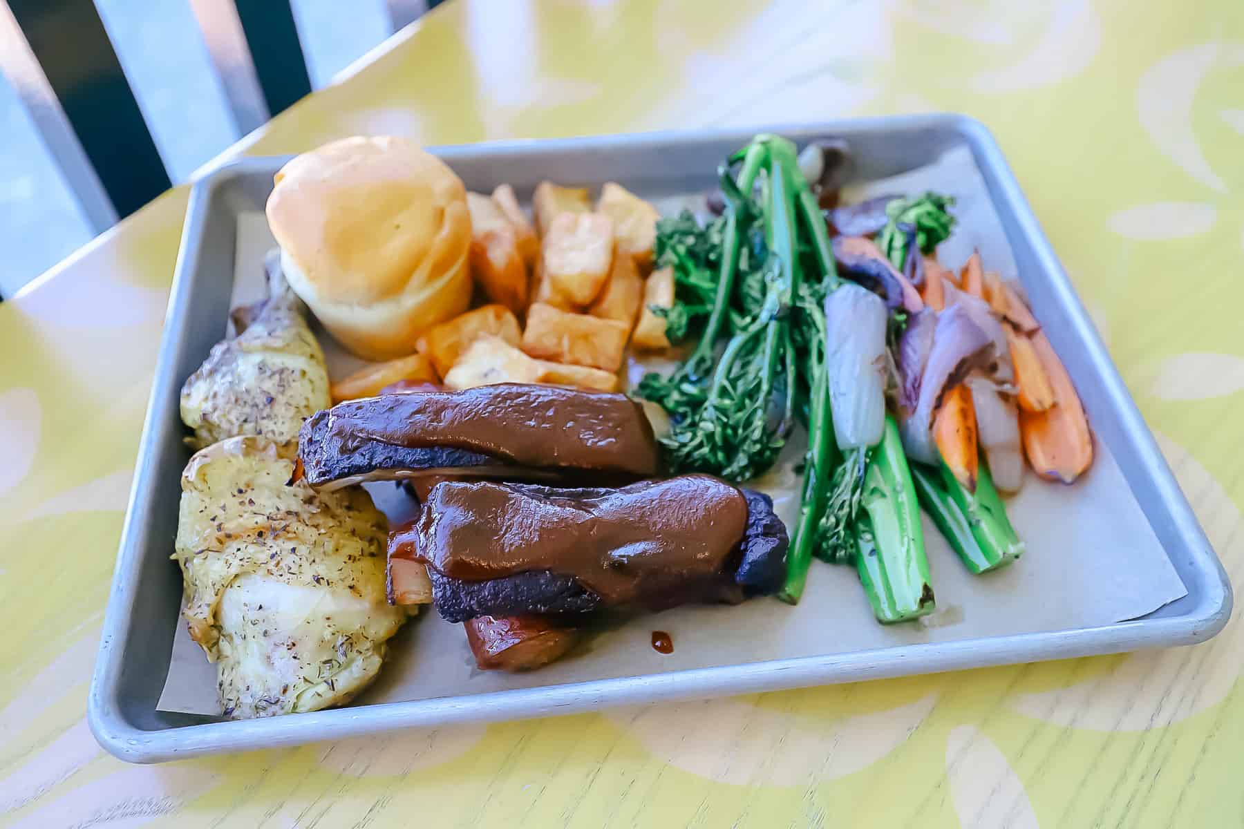 Mixed-grill platter with meats, roasted vegetables, and sides on a white plate