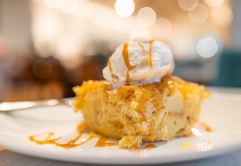 Warm coconut dessert topped with vanilla ice cream and caramel sauce