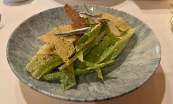 A gourmet salad with crispy elements and fresh greens, served on a rustic plate.