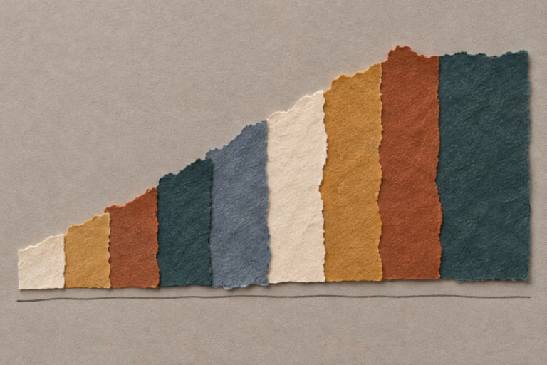 Torn strips of ochre, rust, teal and cream handmade paper arranged as an abstract rising market chart on a warm grey board