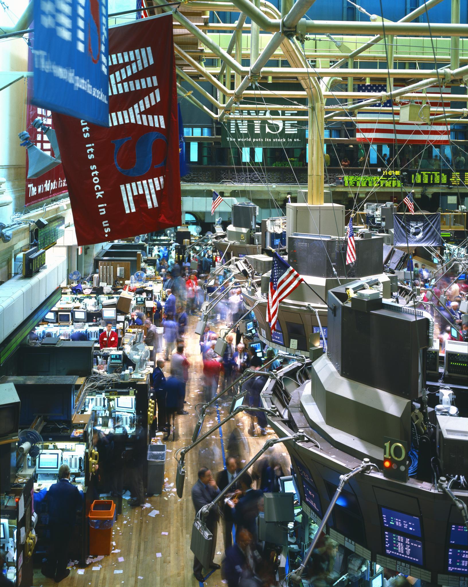 A view over the New York Stock Exchange trading floor with workstations, traders and American flags