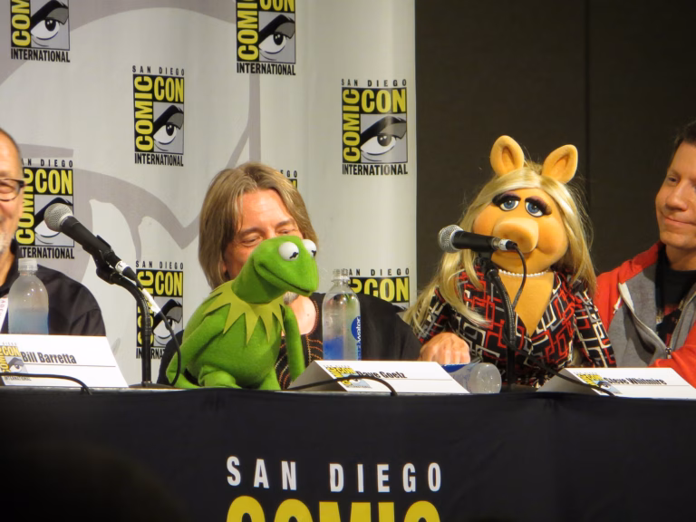 Kermit the Frog and Miss Piggy together behind microphones at a San Diego Comic-Con panel.