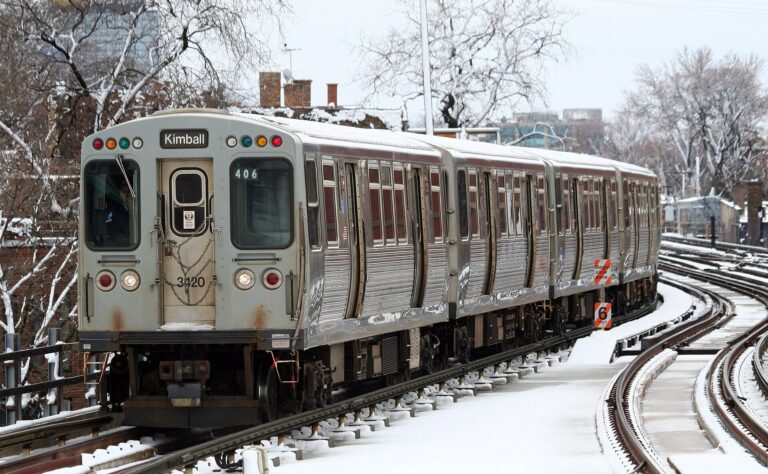 A CTA Brown Line 3200-series train bound for Kimball curves along snow-covered elevated tracks