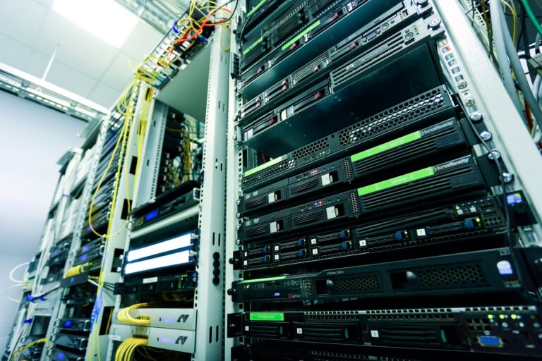 Rack of 1U and 2U servers with yellow and orange patch cabling and blue status lights in a data centre