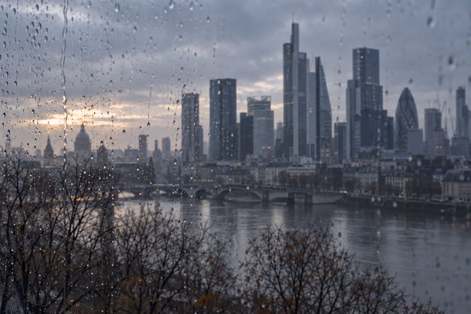 Rain-streaked window overlooking a grey financial-district skyline at dawn