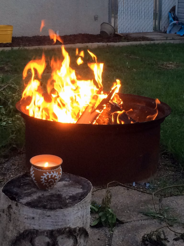 Backyard stone fire pit with wood glowing in the evening