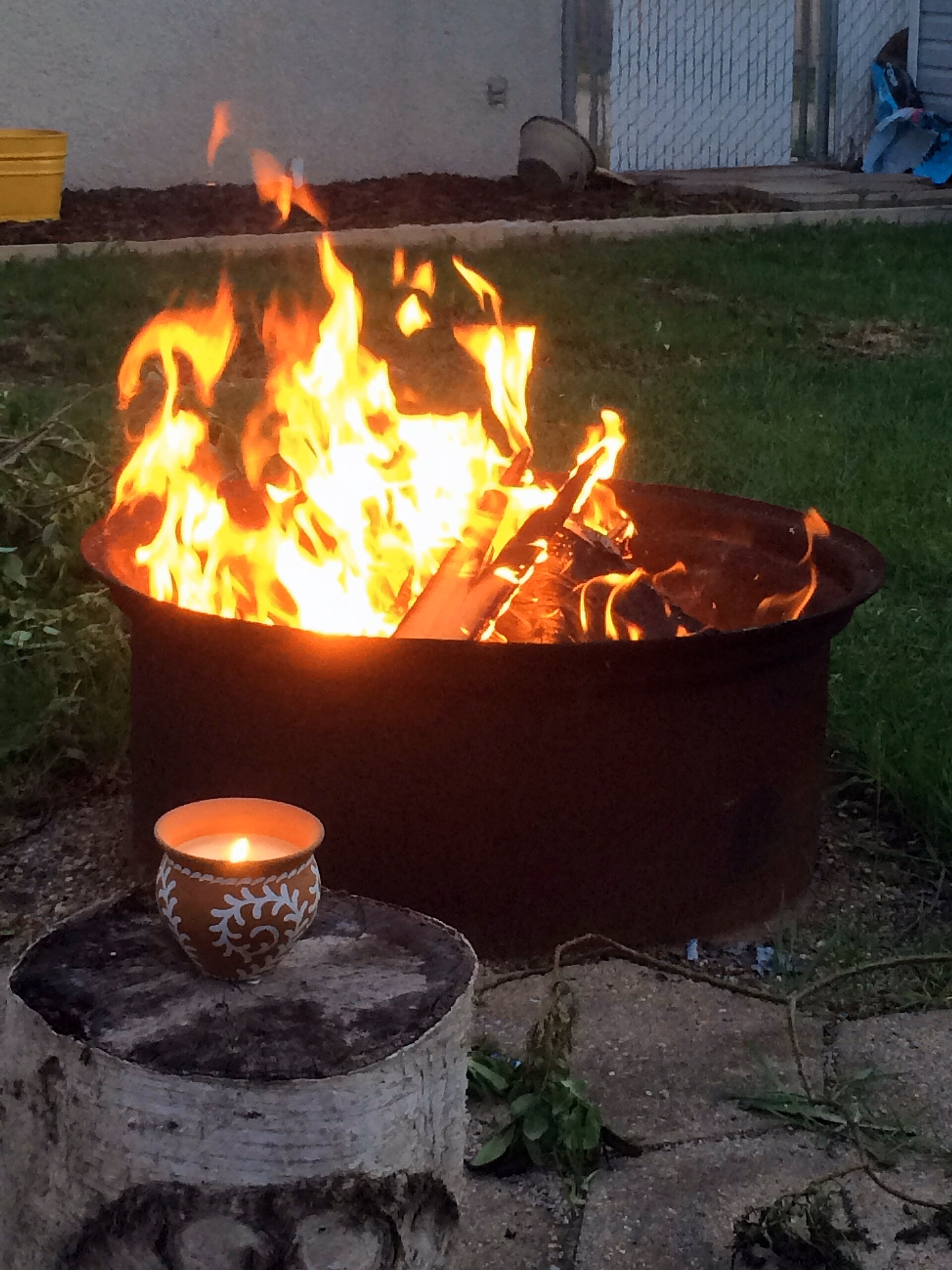 Backyard stone fire pit with wood glowing in the evening