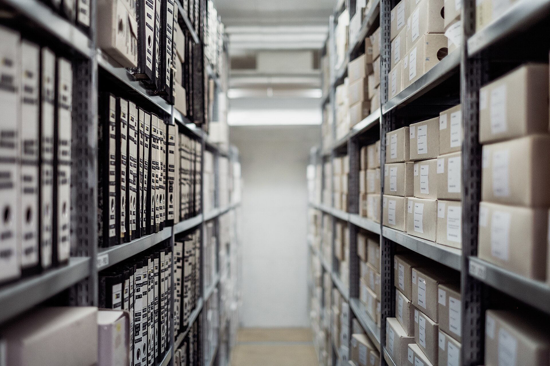 A narrow archive aisle lined with binders and labeled storage boxes.